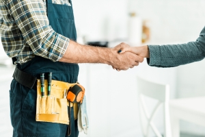 cropped image of plumber and client shaking hands